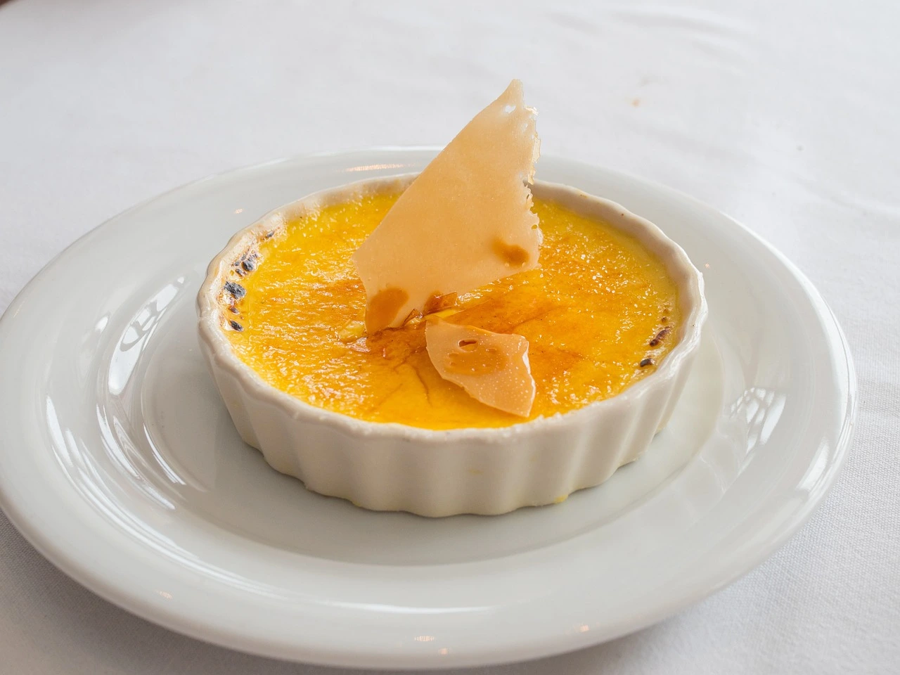 Savory crab brulee topped with a caramelized sugar layer served in a white ramekin.